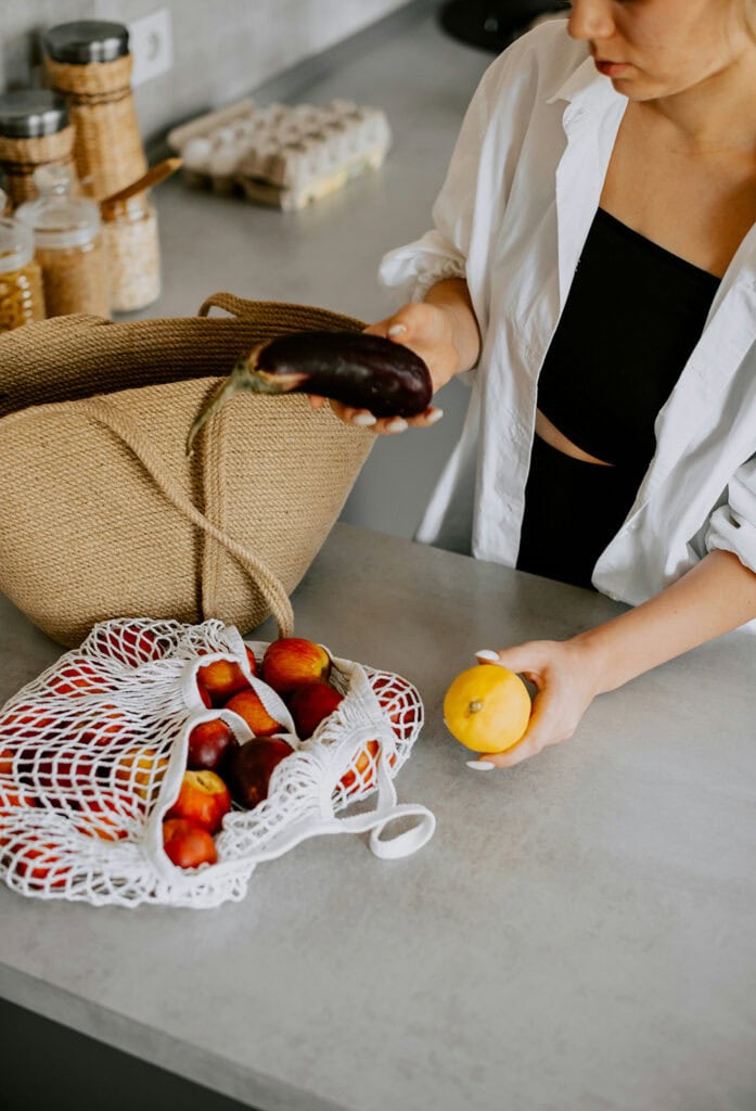 femme tenant un légume avec un fruit sur la table